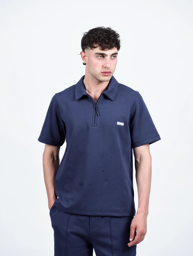 T-shirt à col polo zippé avec badge, porté de face bleu marine